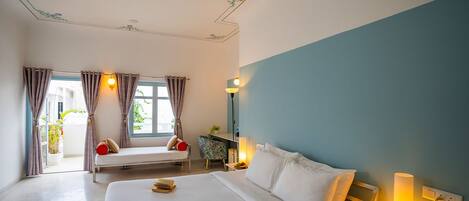 A hotel room with a large bed, a bedside table with a lamp, a window with curtains, and a ceiling with floral decorations.