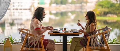Two people dining at a table with a view of a lake and buildings in the background.