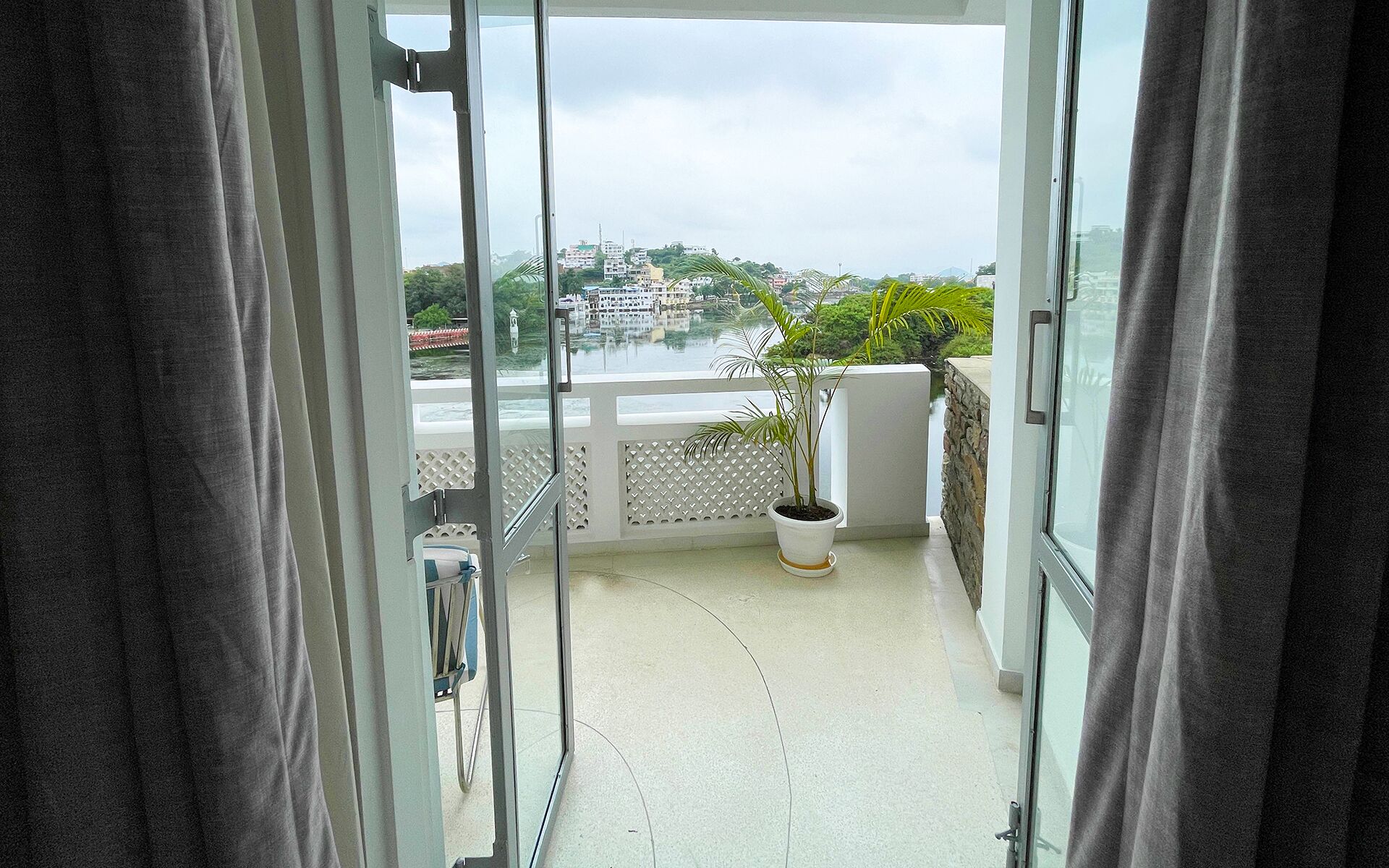 Ein Balkon mit einem Blumentopf, Blick auf eine Stadtlandschaft und einen klaren Himmel.