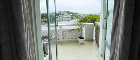 Ein Balkon mit einem Blumentopf, Blick auf eine Stadtlandschaft und einen klaren Himmel.