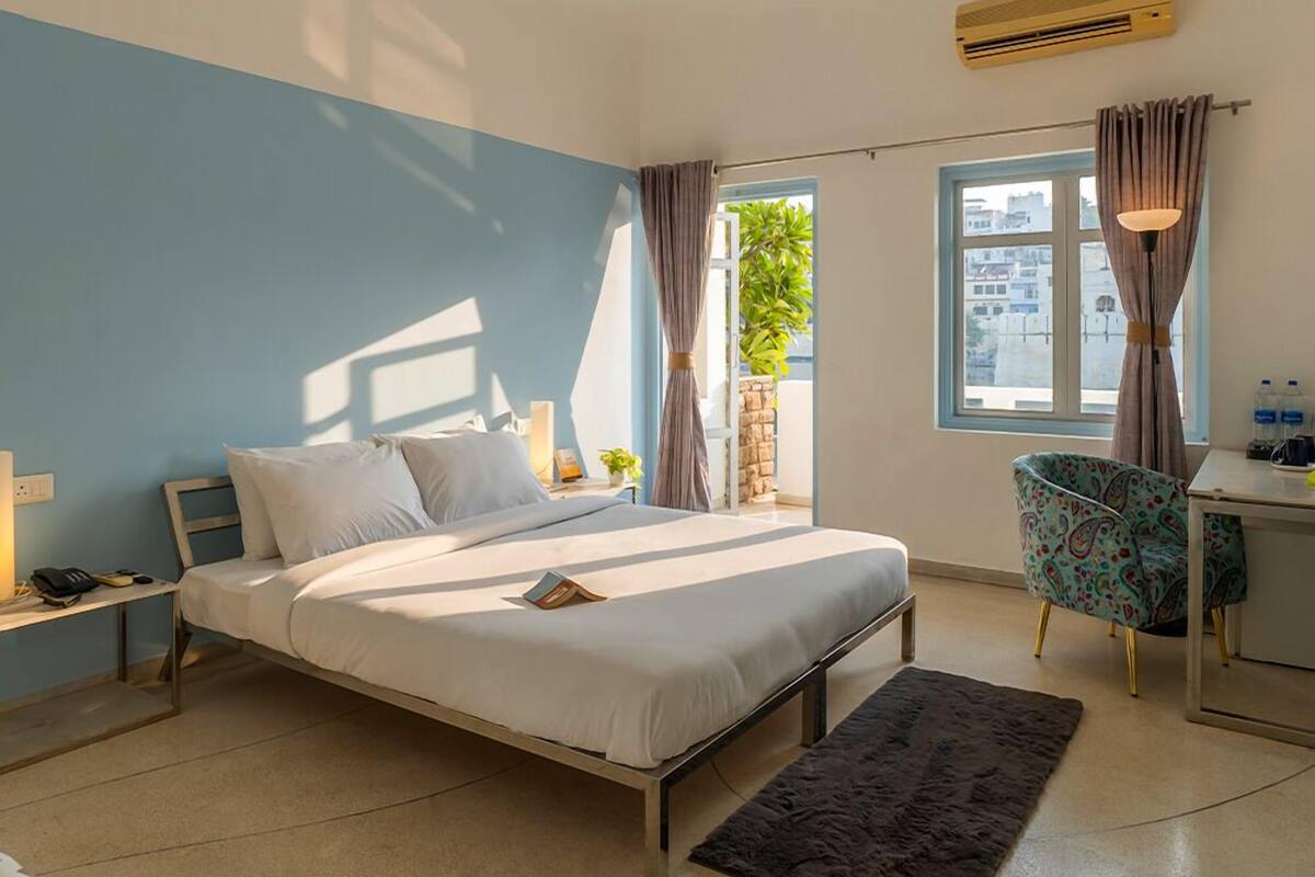 A modern hotel room with a bed, desk, and chair.