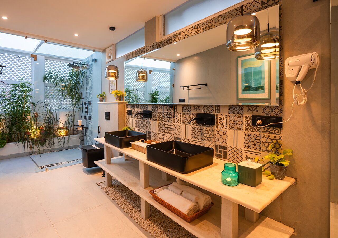 A modern bathroom with a large mirror, black storage bins, a hairdryer, and decorative tiles.