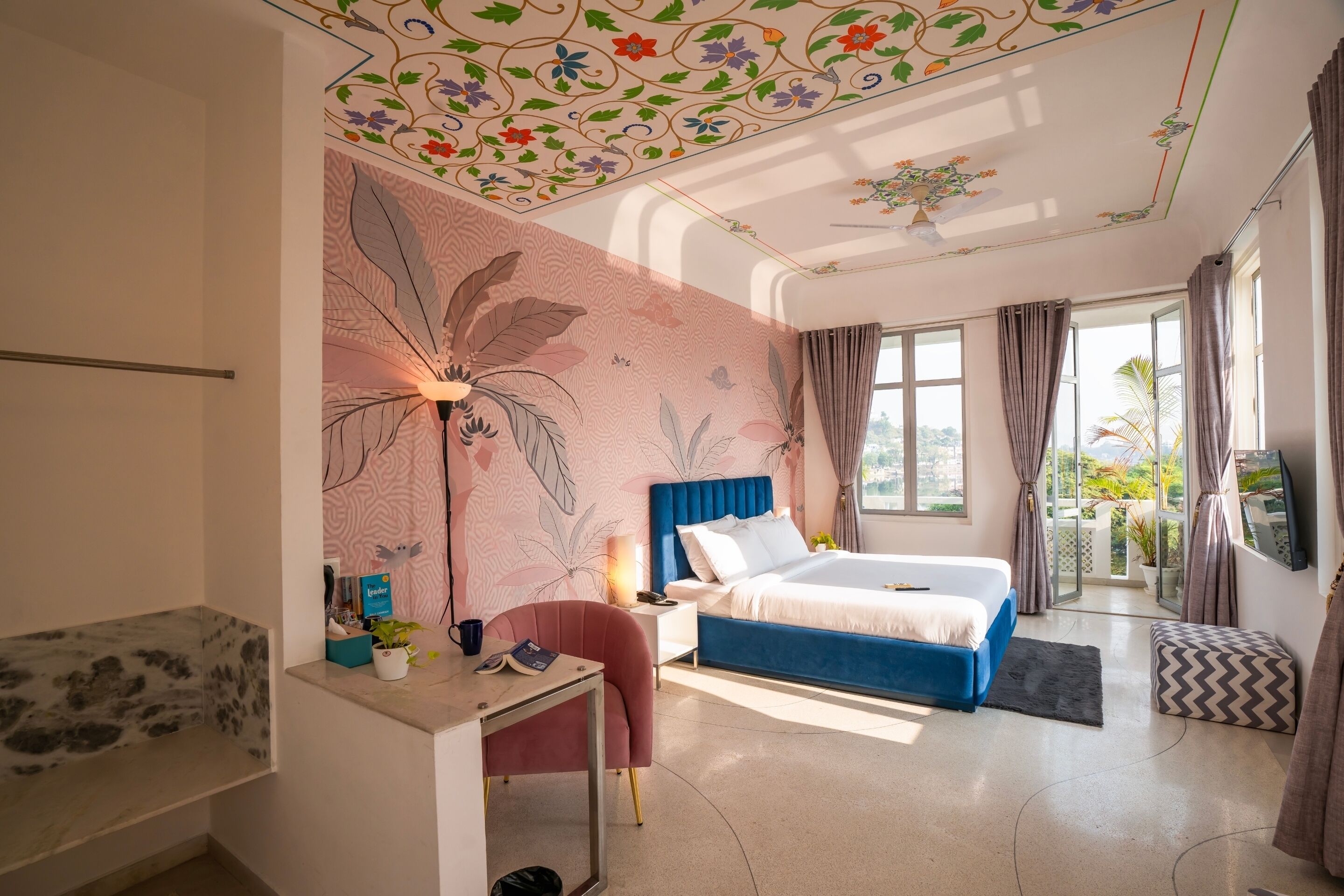 Une chambre d’hôtel moderne dotée d’un grand lit, d’un bureau, d’une chaise et d’un balcon avec des rideaux.
