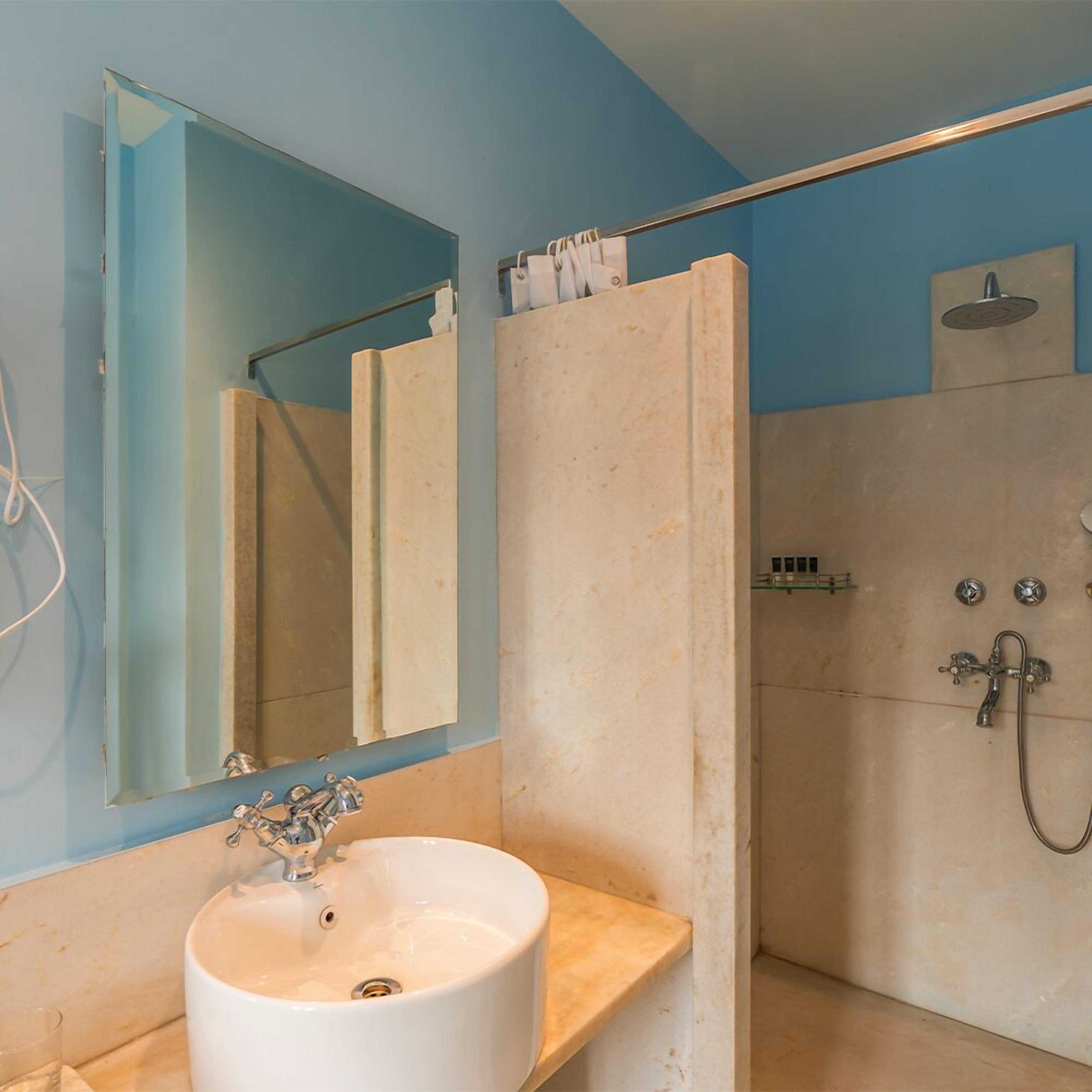 Une salle de bain avec un lavabo blanc, un miroir, une douche et un porte-serviettes.
