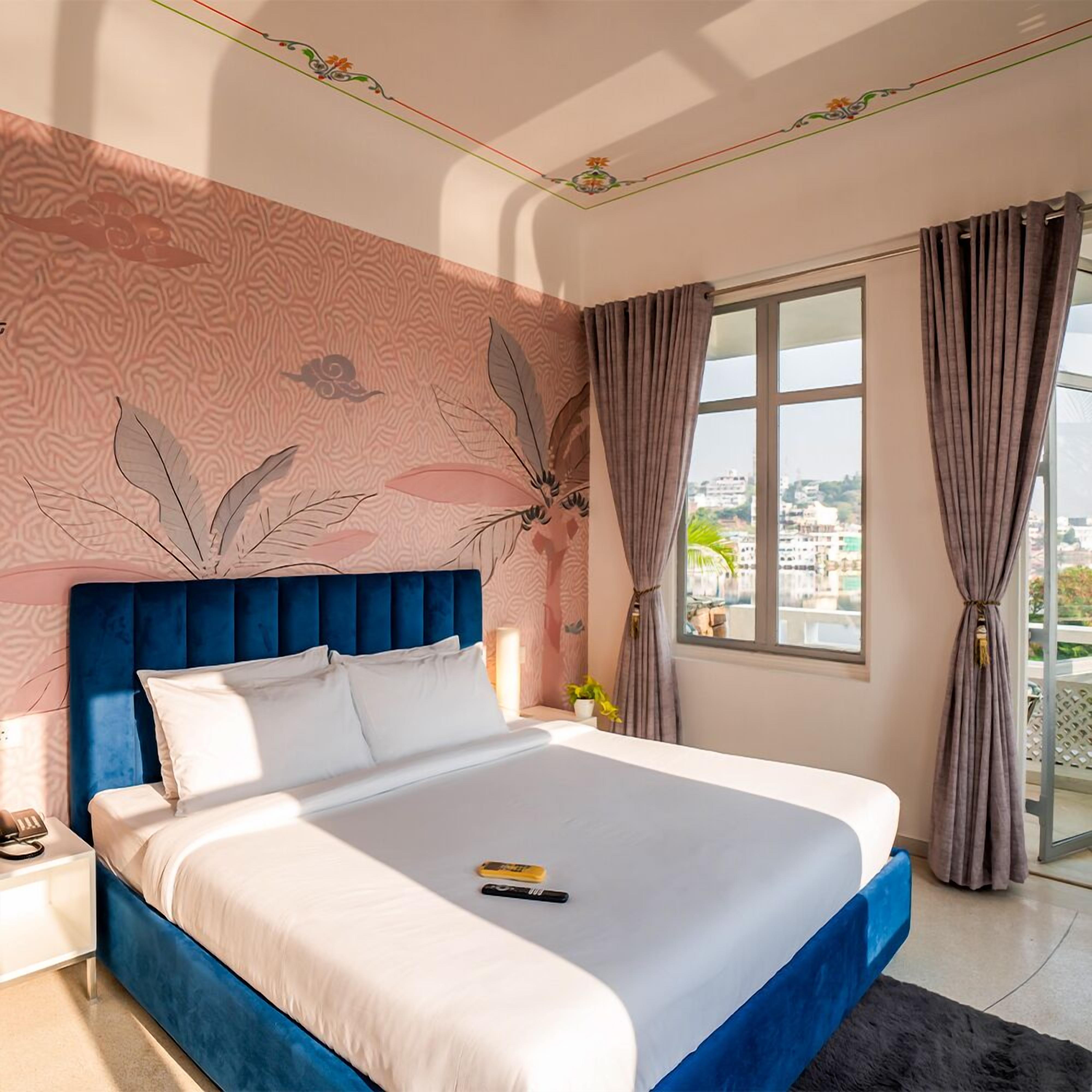 Une chambre avec un grand lit, une table de chevet, une fenêtre avec des rideaux et une vue sur la ville.