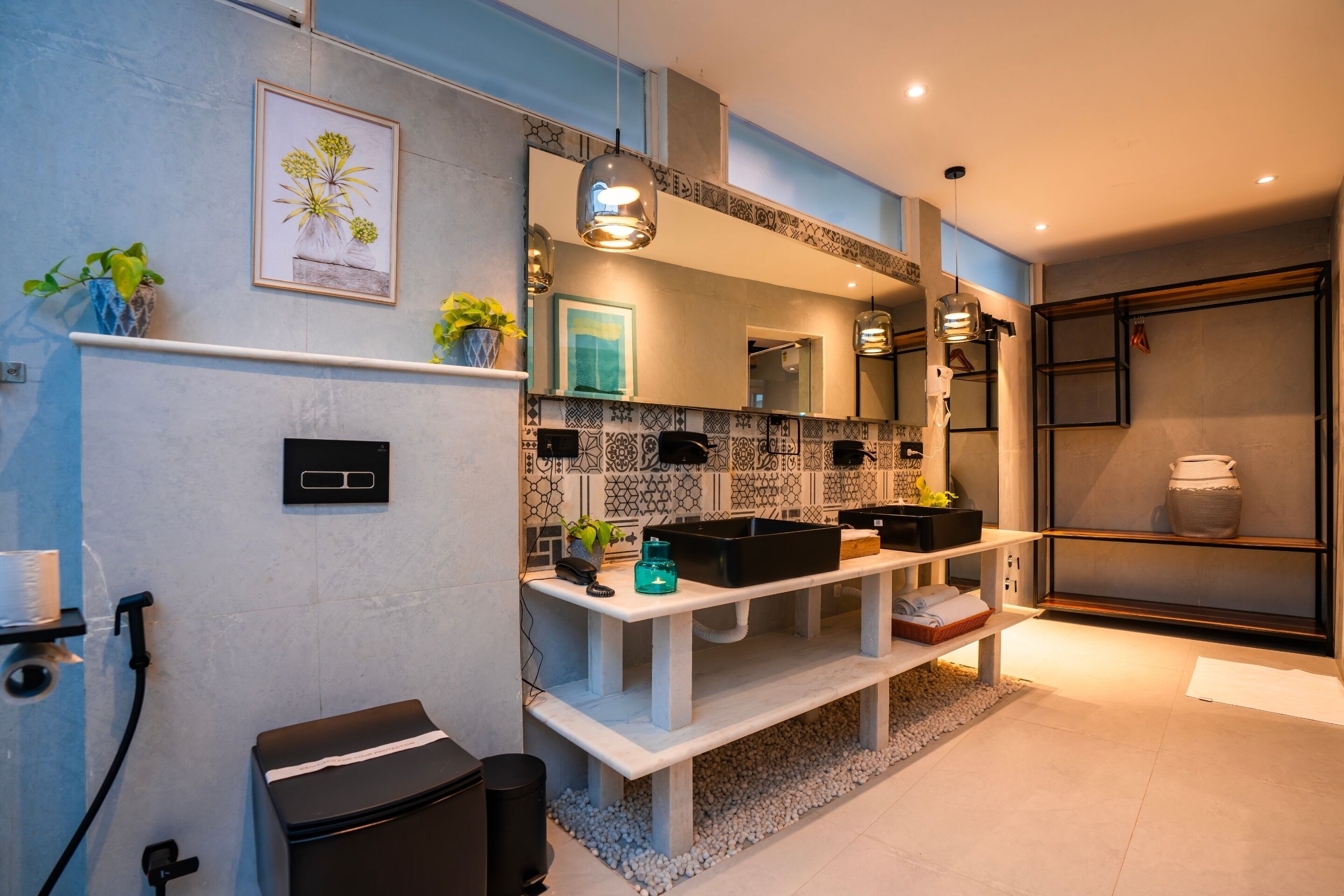 A modern bathroom with a black toilet, a sink with a black countertop, a mirror above the sink, and a shelf with a vase and plants.