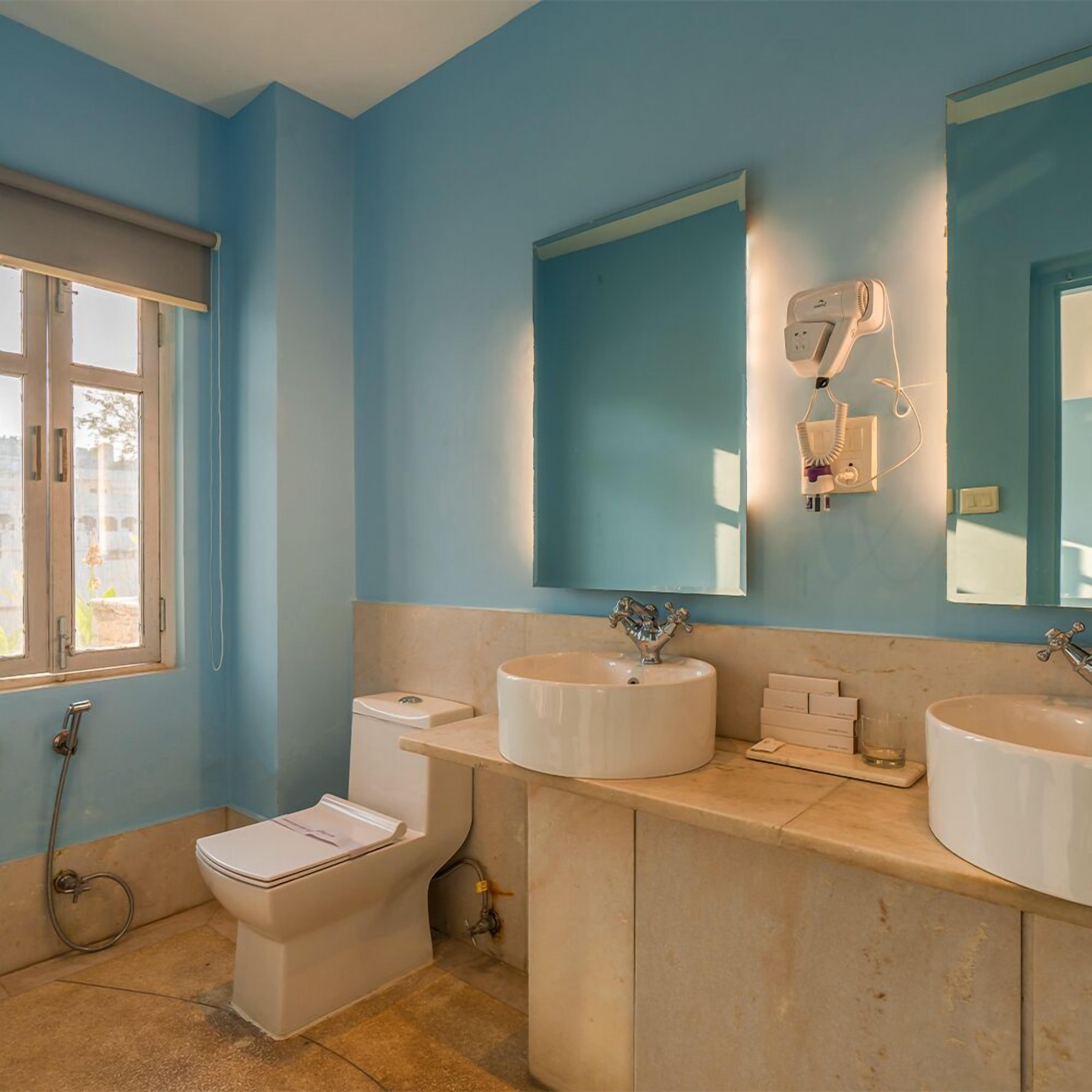 Ein Badezimmer mit zwei Waschbecken, einer Toilette und einem Fenster.