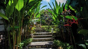 Una escalera de piedra rodeada de exuberante vegetación tropical que lleva a un edificio.
