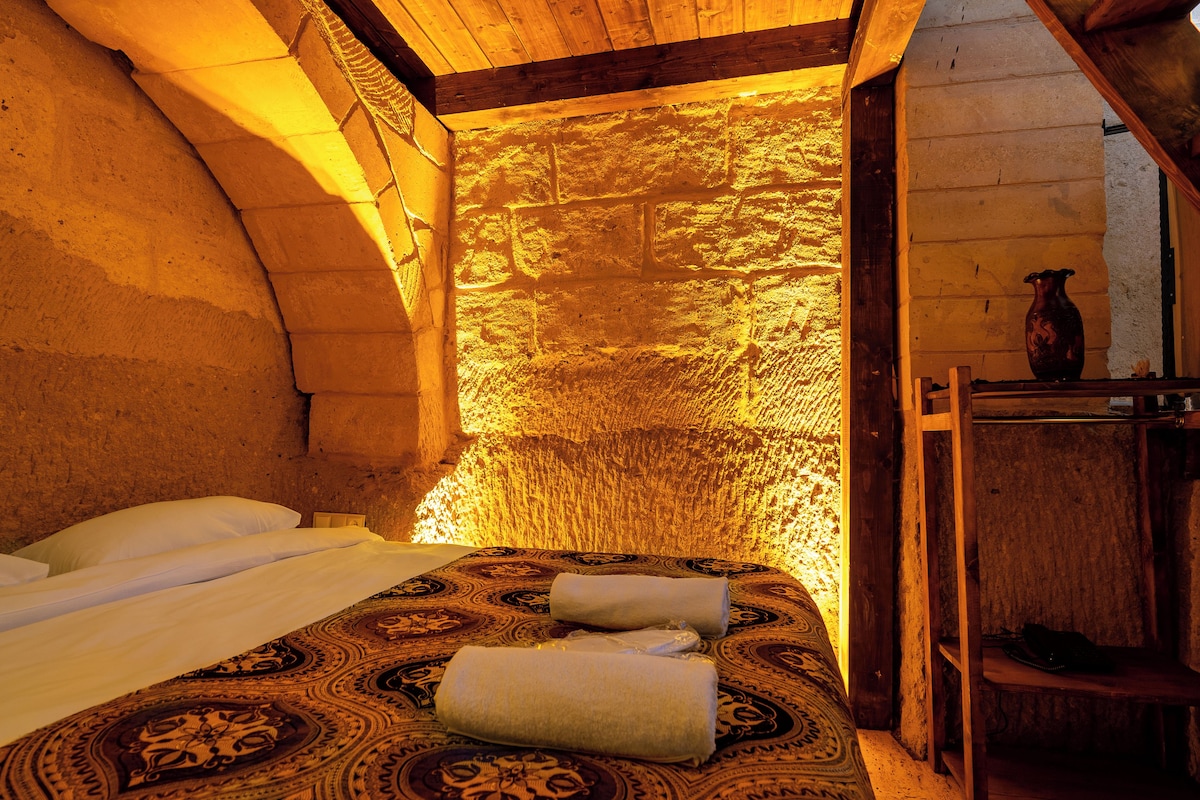 Una habitación acogedora con una cama, un estante de madera y una pared de piedra.
