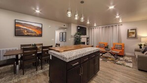 A modern kitchen with a central island, dark cabinetry, and pendant lighting. - Moab Sage Creek Arches Rest (Moab)