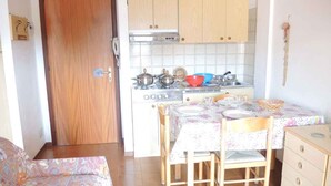 A compact kitchen with wooden cabinets, a dining table with chairs, and a small dresser.