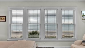 A bedroom with a large window, a bed, a chair, and a small table. - Sandy Toes | Iconic Oceanfront Home with Sunset Views at Grand Pavilion (Isle of Palms)