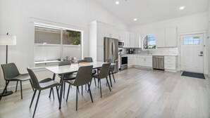 Una cucina moderna con mobili bianchi, una zona pranzo con tavolo e sedie, e un'ampia finestra che offre luce naturale.