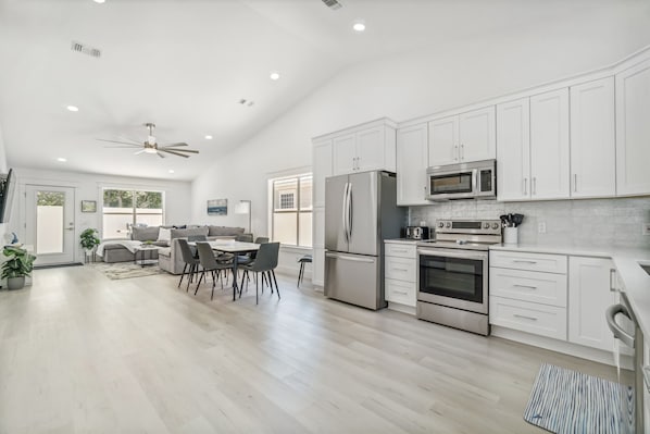 A modern kitchen with white cabinets, stainless steel appliances, and a dining area with a table and chairs.