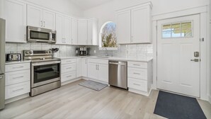Una cucina moderna con mobili bianchi, elettrodomestici in acciaio inossidabile e una grande finestra.