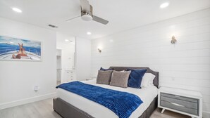 Una camera da letto moderna con un letto grande, un ventilatore a soffitto, illuminazione a incasso e un comodino.