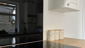A modern kitchen with a black induction cooktop, stainless steel appliances, and a wooden countertop. - Gillingham cosy 3 bedroom with free WiFi & parking (Gillingham)