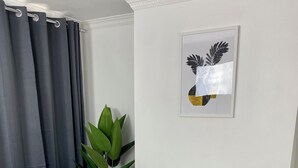 A dining area with a white table, four white chairs, and a vase with a plant. - Gillingham cosy 3 bedroom with free WiFi & parking (Gillingham)