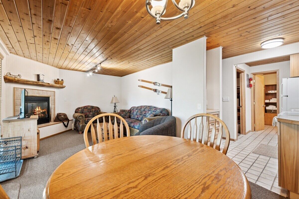 A cozy living room with a fireplace, a dining table, and a sofa.