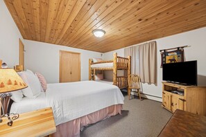 A room with a bunk bed, a desk, a television, and a lamp.