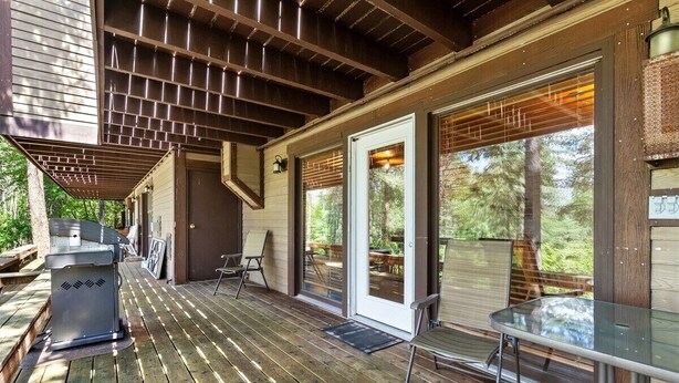 An outdoor deck with a grill, seating, and a covered area with sliding glass doors.