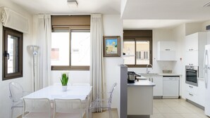 A modern kitchen with white cabinets, a built-in oven, and a dishwasher. - MAMAD Airy & Bright with Balcony & Parking steps from Beach by FeelHome (Tel Aviv - Jaffa)