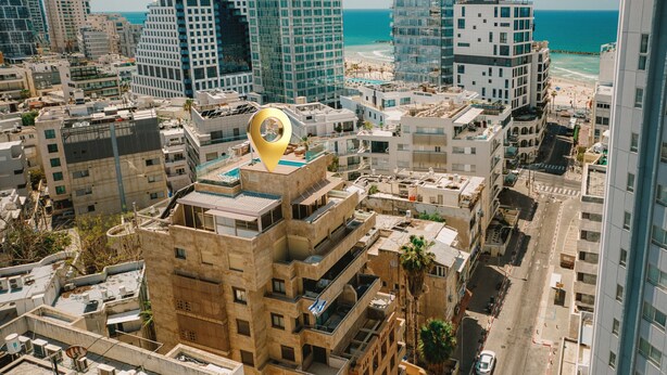 A high-rise urban area with multiple buildings, a prominent golden location marker, and a beach in the background. - MAMAD Airy & Bright with Balcony & Parking steps from Beach by FeelHome (Tel Aviv - Jaffa)