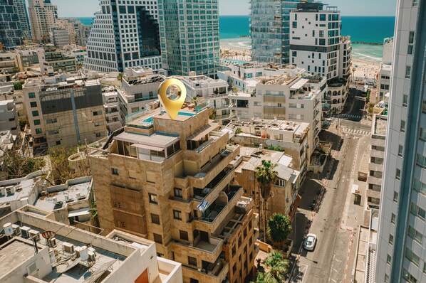 A high-rise urban area with multiple buildings, a prominent golden location marker, and a beach in the background.