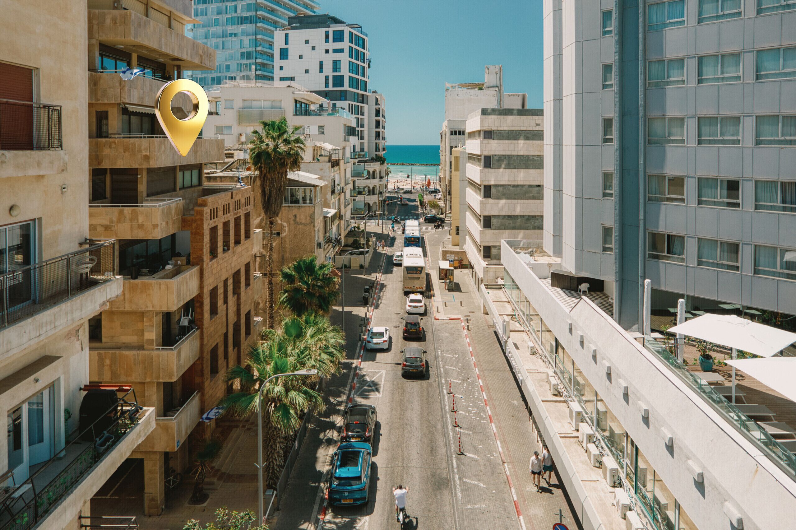 Une rue urbaine animée, bordée d’immeubles, avec des voitures garées et une vue dégagée sur la mer.