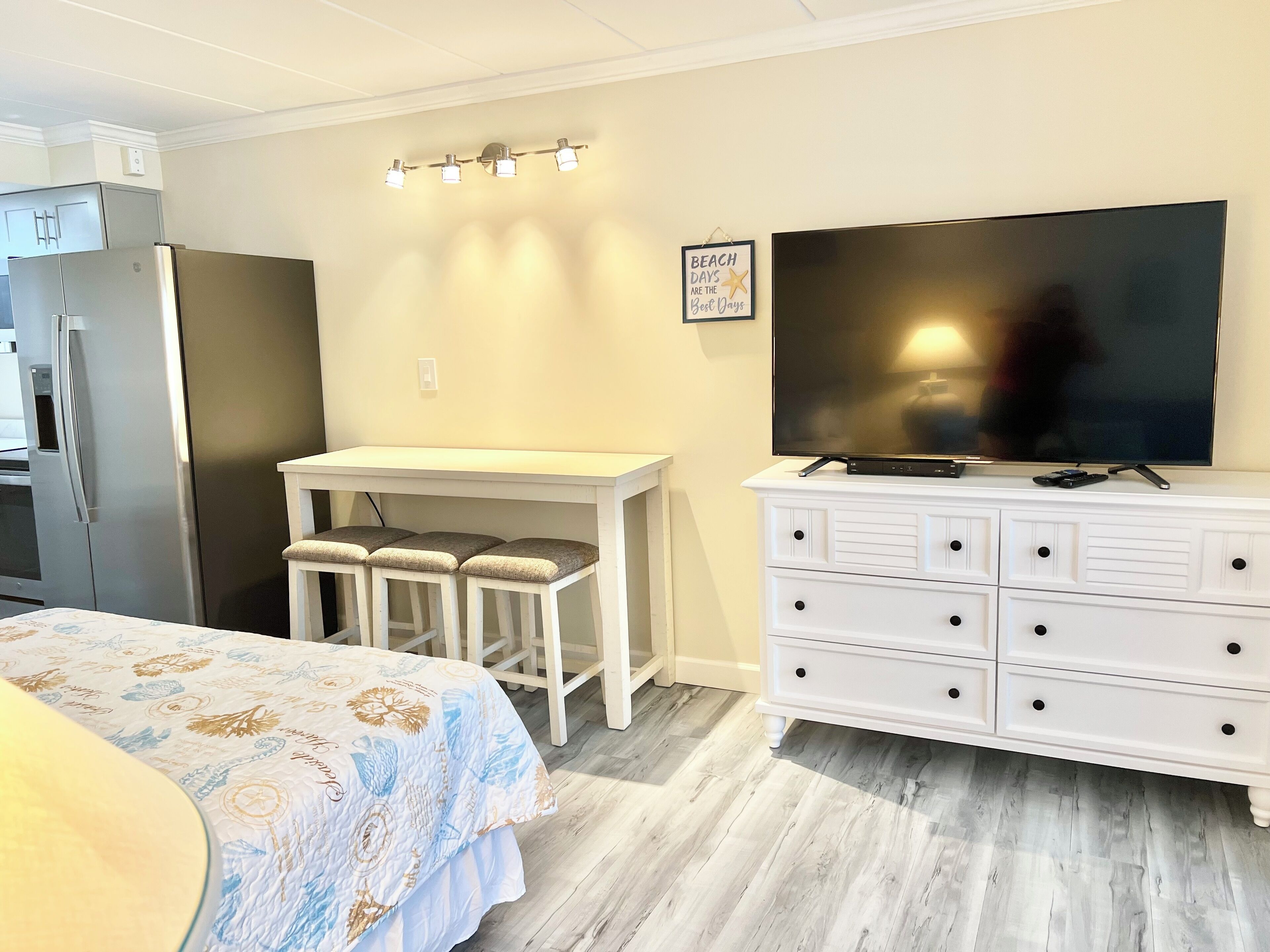 A bedroom with a bed, a TV, a desk, and a dresser.