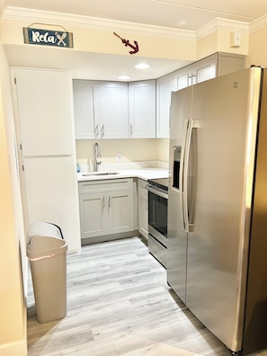 Una cocina moderna con armarios blancos, un refrigerador de acero inoxidable y un horno empotrado.