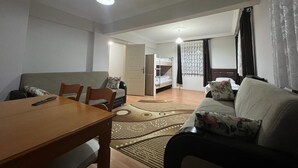 A compact living space with a dining table, sofa, and a bunk bed in the background. - Uzungöl (Çaykara)