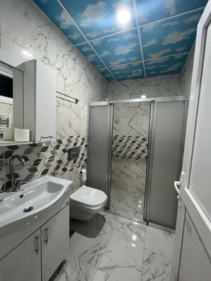 A bathroom with a marble floor, a shower with glass doors, and a sink with a mirror. - Uzungöl (Çaykara)