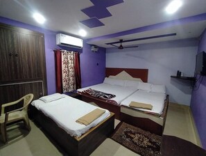 A hotel room with two beds, a wardrobe, a chair, an air conditioning unit, and a ceiling fan. - Sea Dream Lodge (Puri)