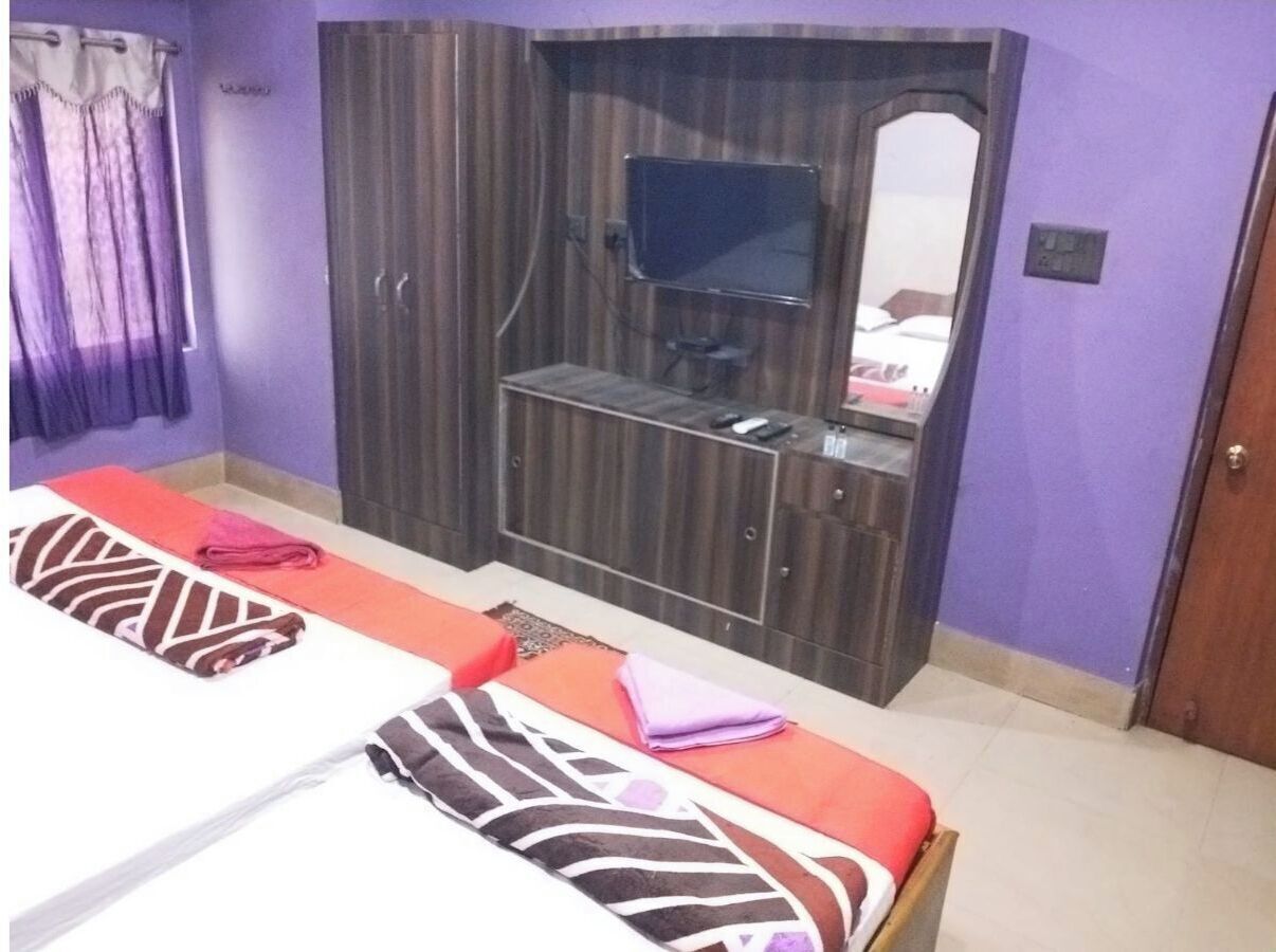 Une chambre avec deux lits, une télévision et une armoire.
