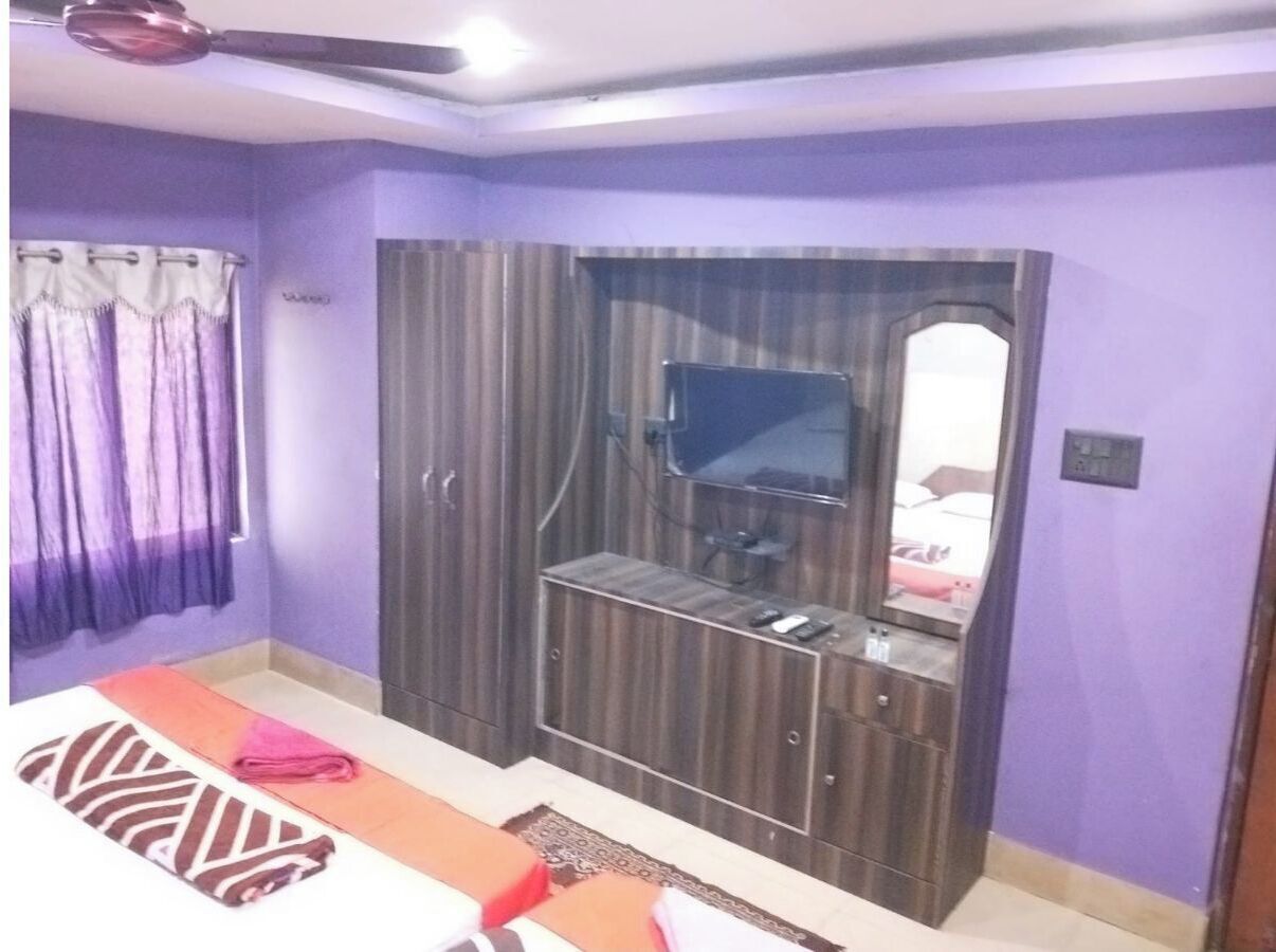 A bedroom with a bed, a TV, a wardrobe, and a mirror.