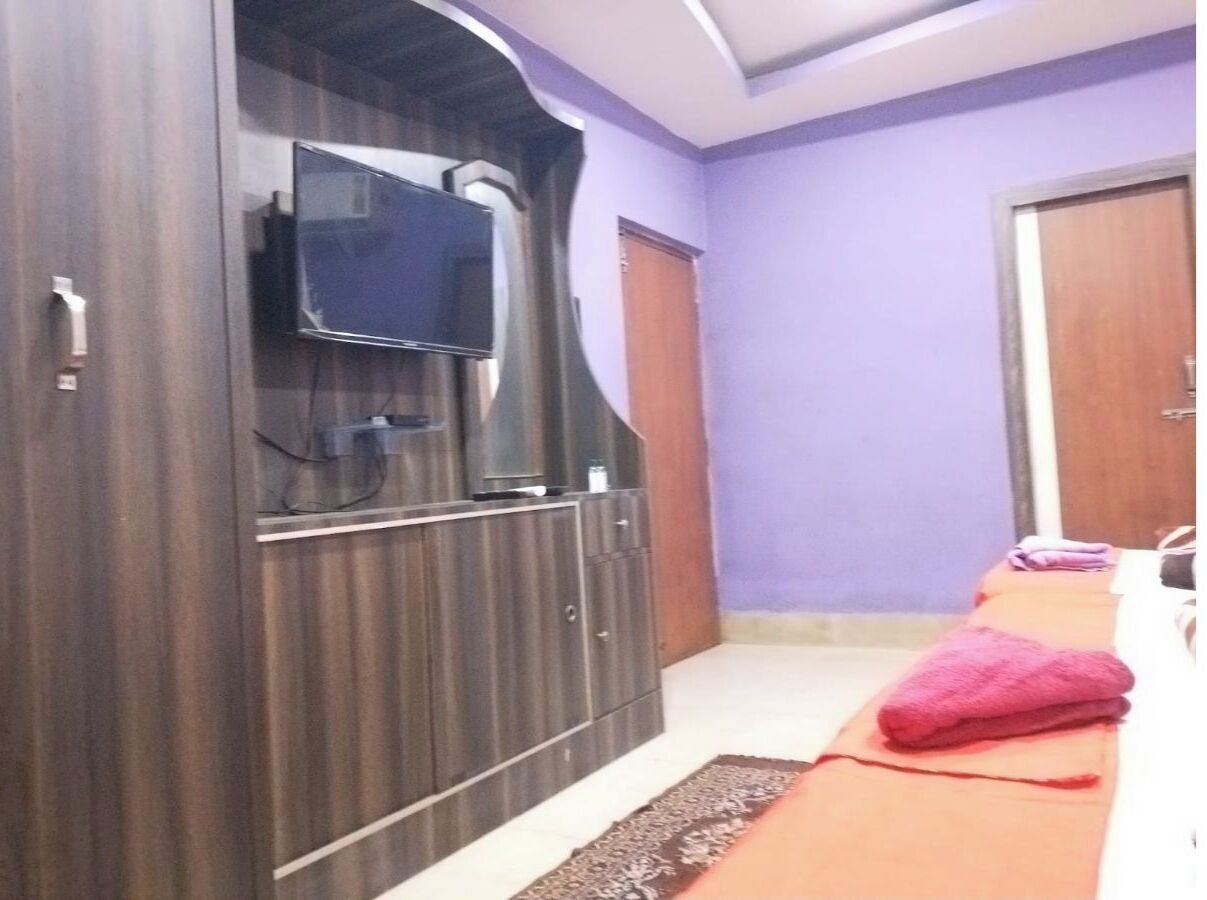 Een kamer met een grote kast, een flatscreen-tv die erop bevestigd is, en een massagetafel met een roze handdoek.