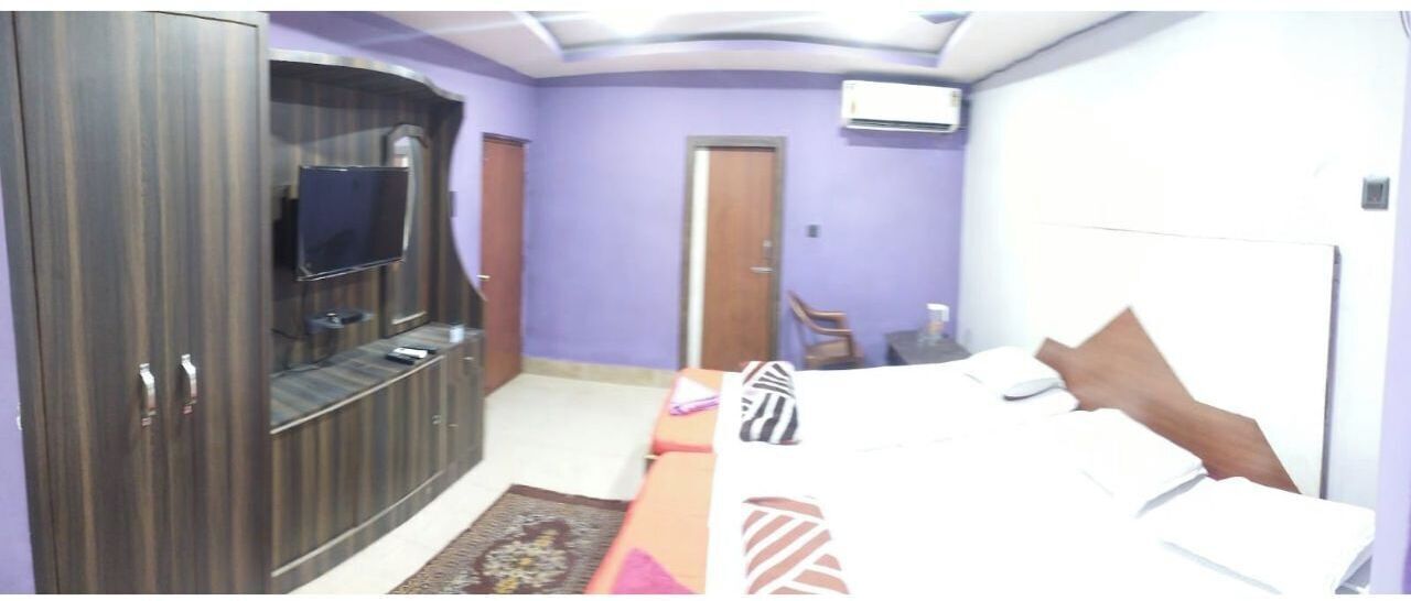 A bedroom with a bed, a TV, a wardrobe, and a door.