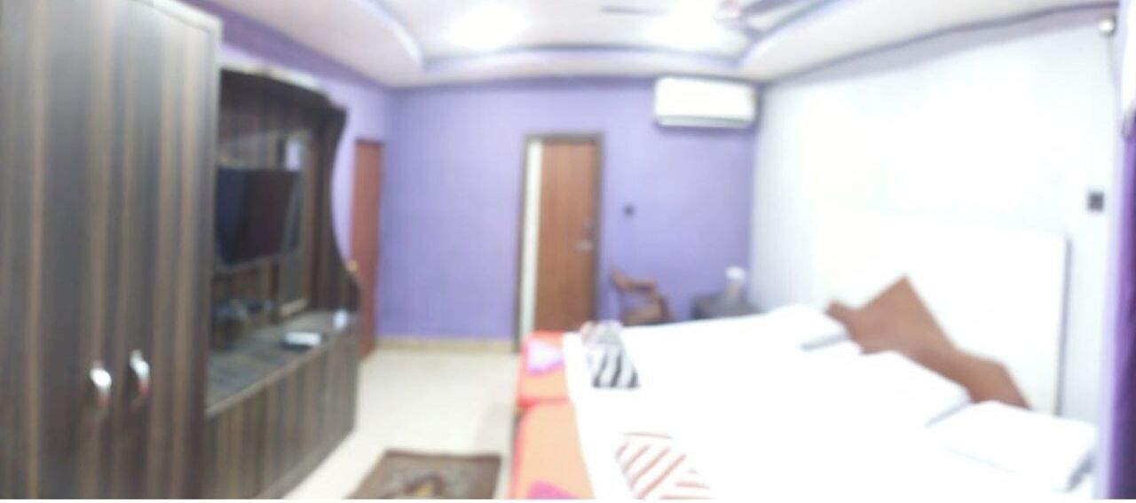 A bedroom with a bed, a wardrobe, a television, and a door.