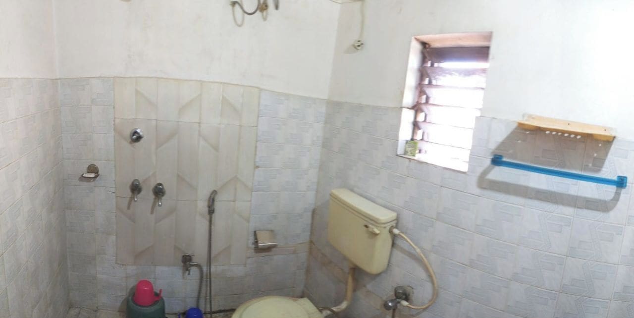 A small bathroom with a toilet, a shower, and a window.