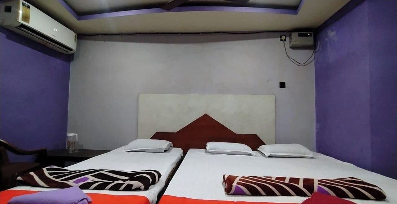 Ein Zimmer mit zwei Betten, violetten Wänden und einer Klimaanlage.