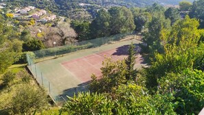 A tennis court surrounded by lush greenery and houses on a hillside. - Appartement "rooftop" Avec Très Grande Terrasse à 2km de la mer (Roquebrune-sur-Argens)