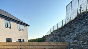 Une terrasse extérieure avec des meubles en osier, un sol en pierre et une clôture en bois.