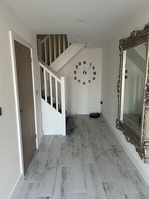 Staircase leads to an upper level, flanked by a decorative clock and ornate mirror.