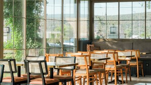 Un espace de détente intérieur moderne, doté de grandes fenêtres, de chaises et de tables en bois.