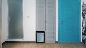 Une pièce dotée d’une porte-fenêtre coulissante, d’un placard gris fermé et d’une porte turquoise ornée de motifs décoratifs.