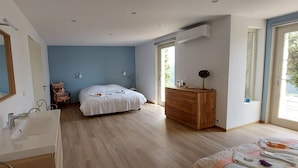 Ein Schlafzimmer mit einem Bett, einer Holzkommode, einem weißen Waschbecken und einem Spiegel.