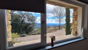 Ein Fenster mit Blick auf eine Steinsäule, einen Baum und eine Landschaft.