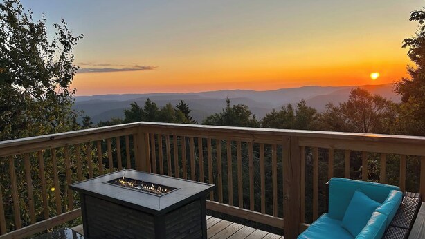A deck with a fire pit and a blue sofa, overlooking a sunset and distant hills. - Hutch 1- 2 Min Walk to Slopes, Great Mountain View (Slaty Fork)