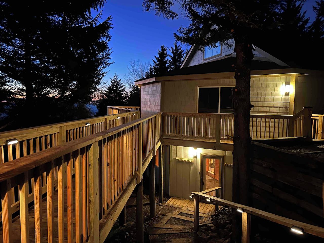 A two-story wooden structure with a balcony and a staircase leading to the upper level.